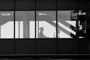 Silhouette of a person working at a desk in an office.